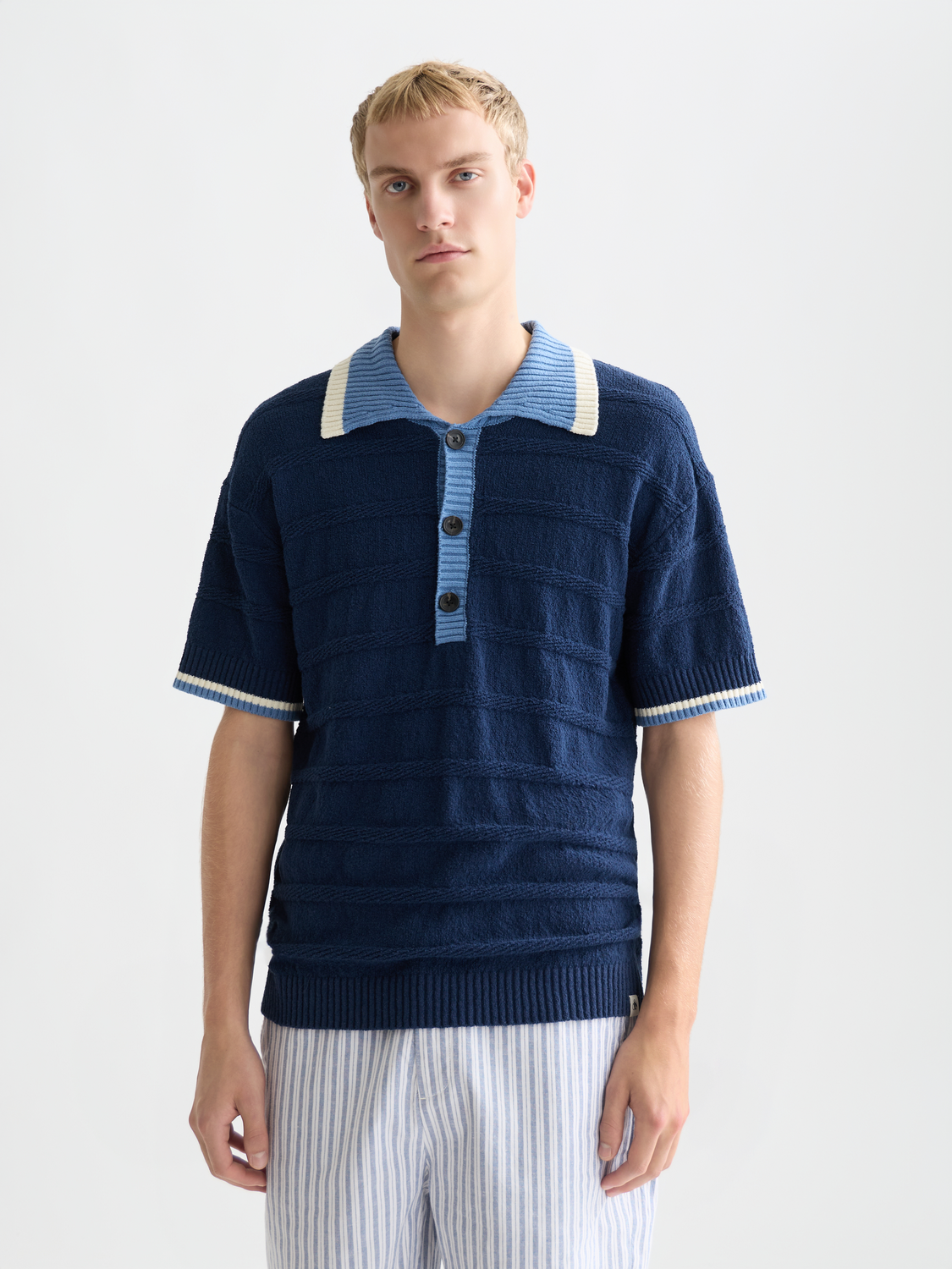 SCOTCH & SODA knitted polo shirt in cream color, close-up showing textured knit fabric and classic collar detail.