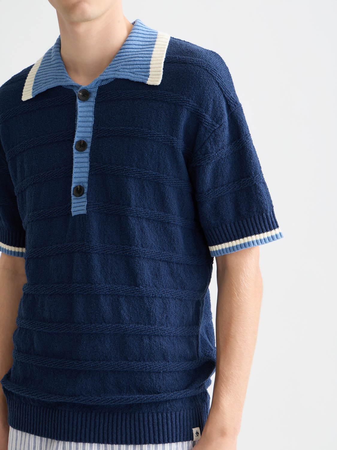 Knitted SCOTCH & SODA polo shirt with a classic collar and textured knit fabric, shown in a neutral color.