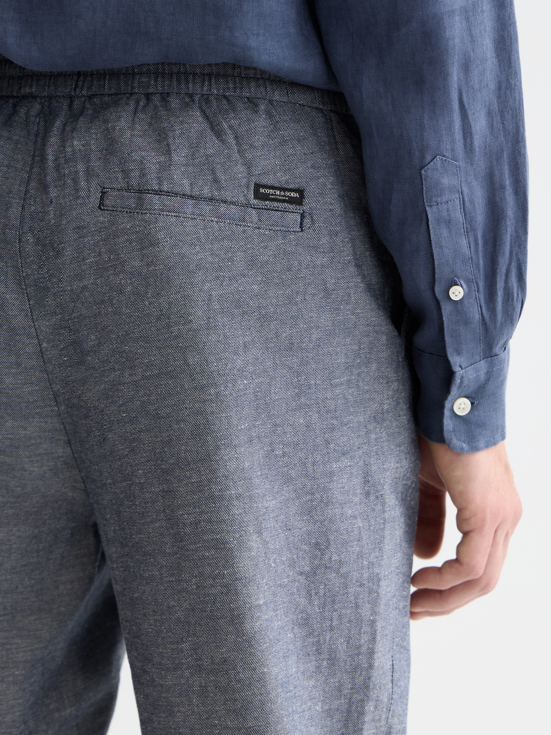 SCOTCH & SODA Warren jogger pants in neutral fabric with relaxed fit and tapered design, shown in a casual outdoor setting.