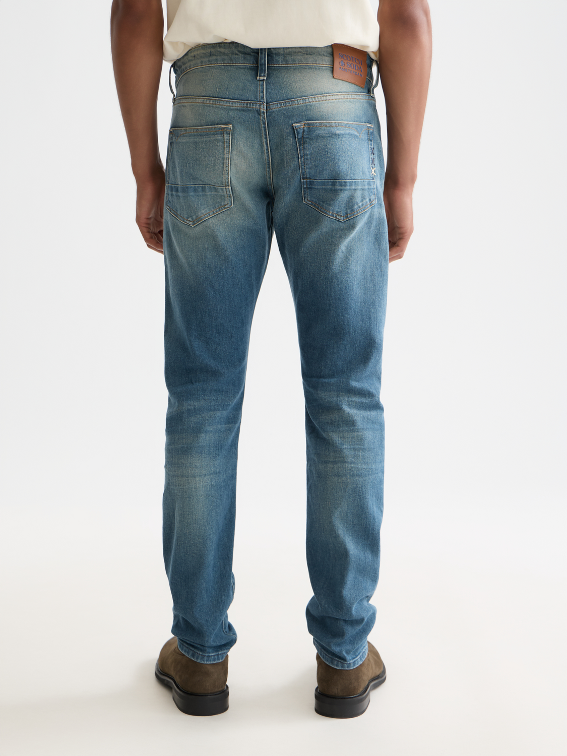 Dark blue Scotch & Soda Ralston slim-fit denim jeans displayed from the back with visible stitching and a leather patch on the waistband.