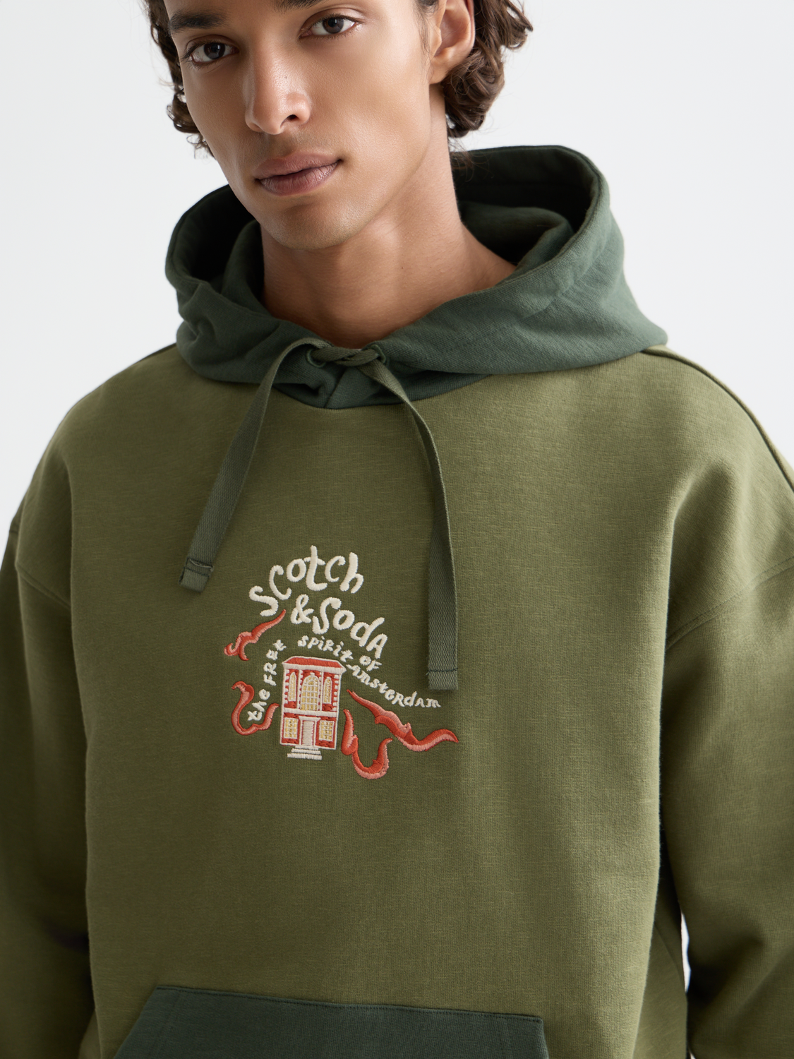Embroidered hoodie from Scotch & Soda featuring detailed stitching and a comfortable fit, shown in a stylish casual wear setting.
