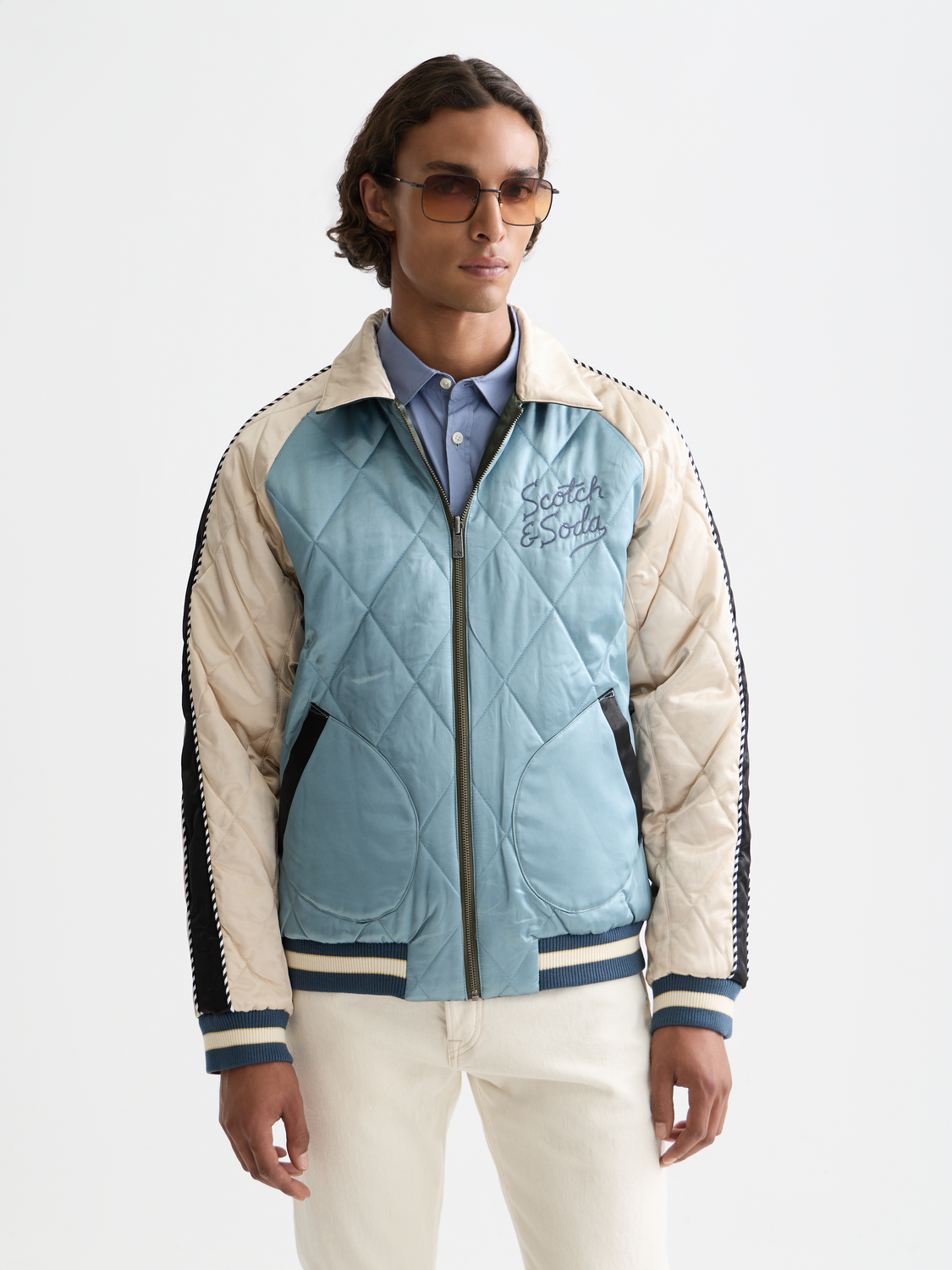 Reversible souvenir bomber jacket by Scotch & Soda, featuring vibrant printed and solid fabric sides, displayed on a hanger.