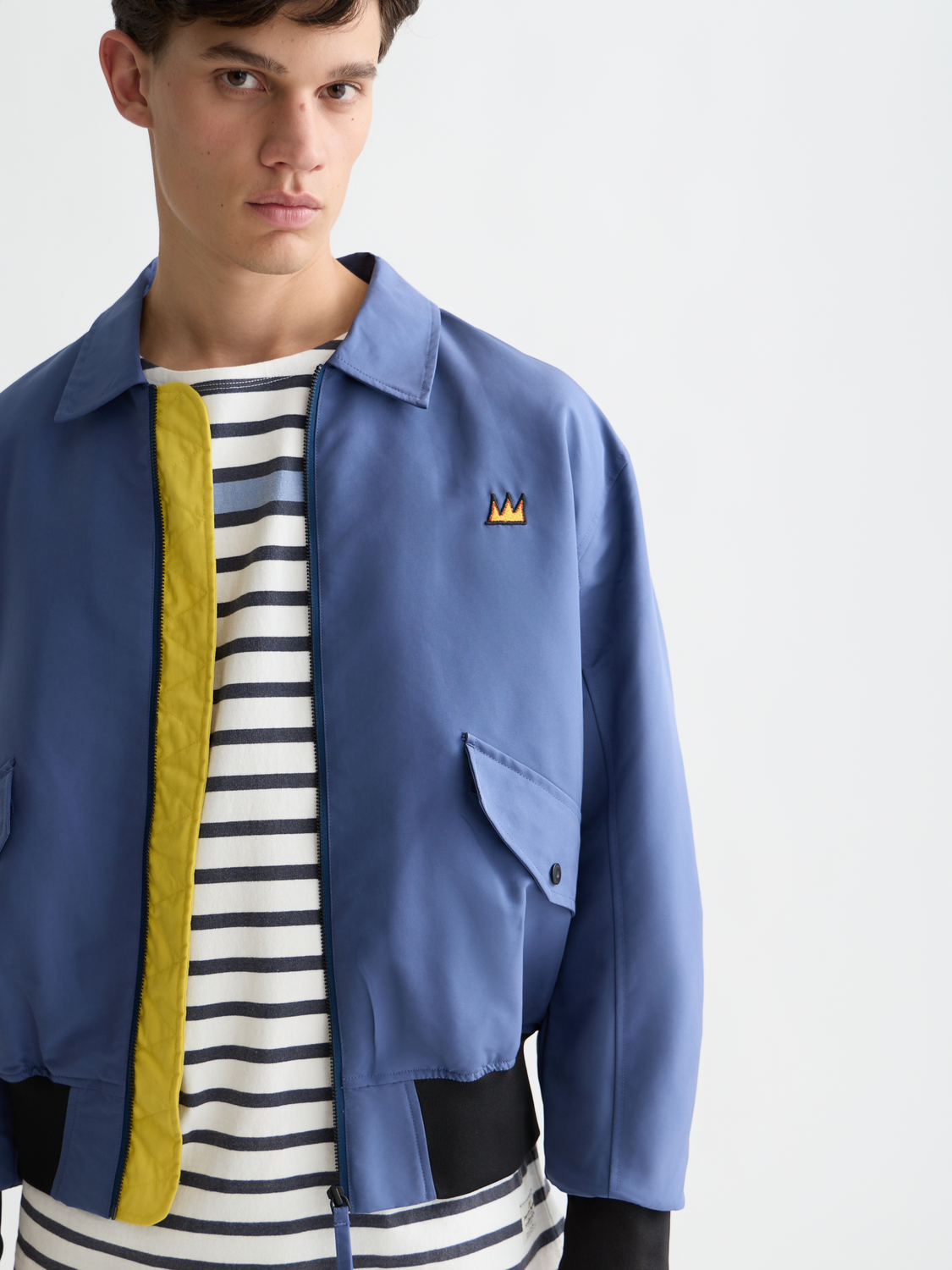 SCOTCH & SODA S&S x Basquiat souvenir jacket with vibrant artwork, front zipper, and ribbed cuffs, displayed on a hanger.