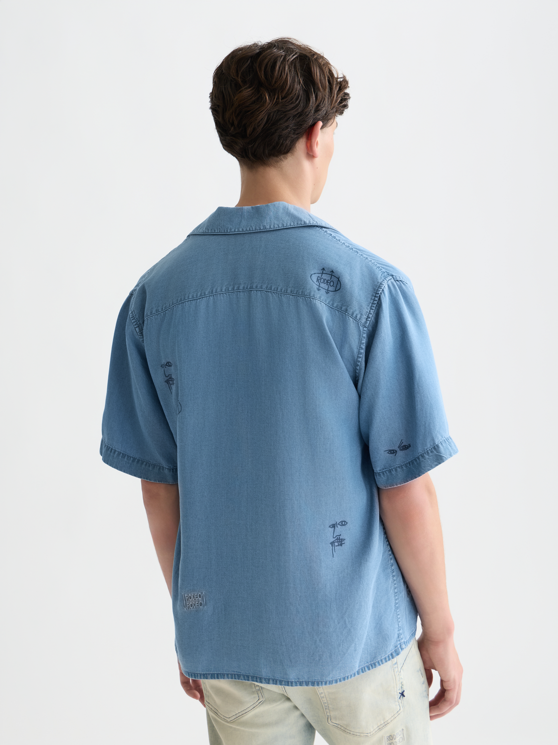 Indigo short-sleeved shirt by Scotch & Soda featuring Basquiat-inspired artwork, displayed from the back view.