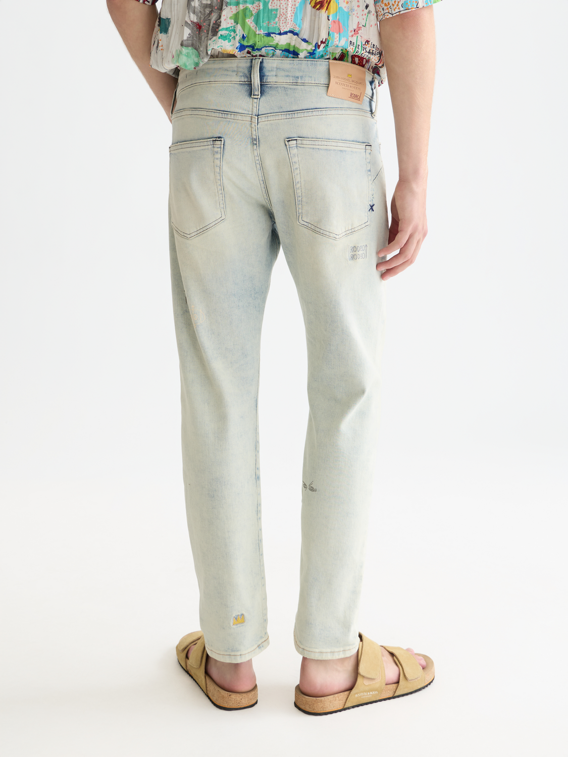 Blue denim Zee straight-fit jeans by S&S x Basquiat for Scotch & Soda, showing back view with classic five-pocket design.