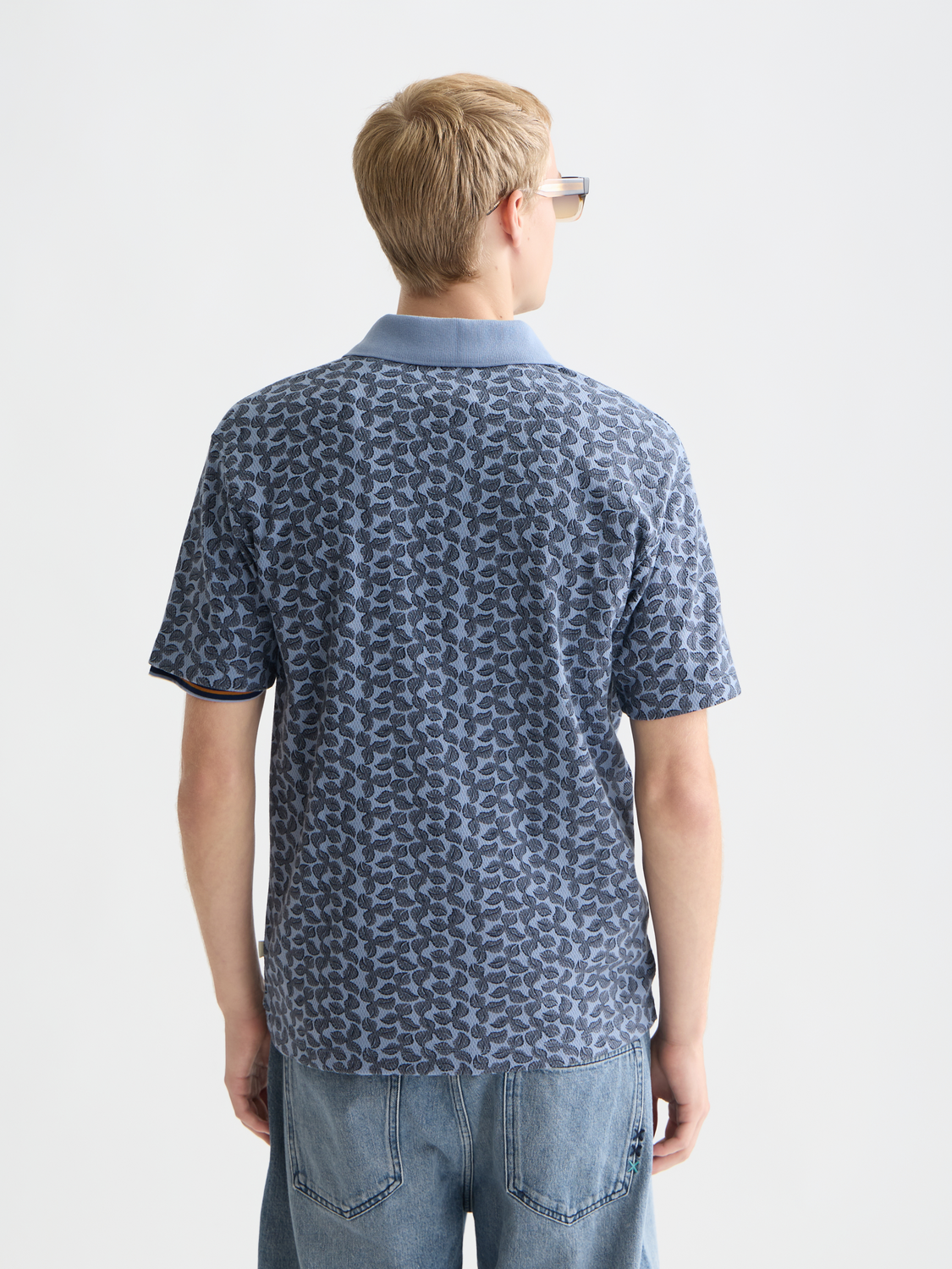 Printed Scotch & Soda polo shirt with colorful pattern, short sleeves, and classic collar, displayed on a hanger.