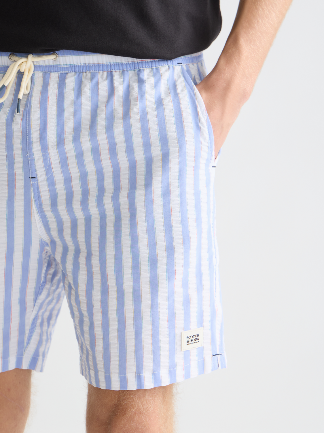 Striped mid-length swimshorts by Scotch & Soda featuring blue and white horizontal stripes, casual swimwear for men.