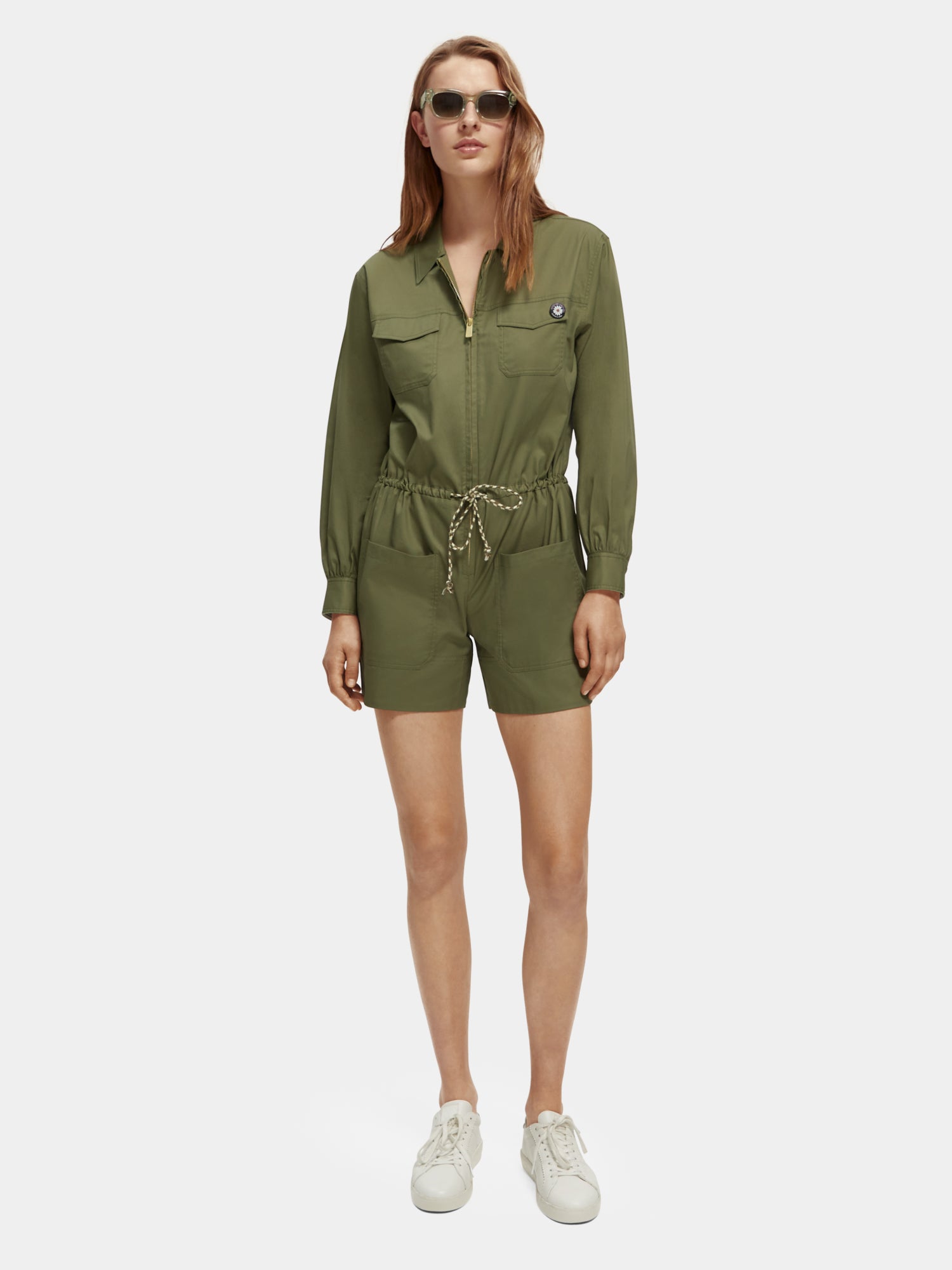Military-style playsuit jumpsuit by Scotch & Soda featuring a fitted design and front button closure, shown in the image.