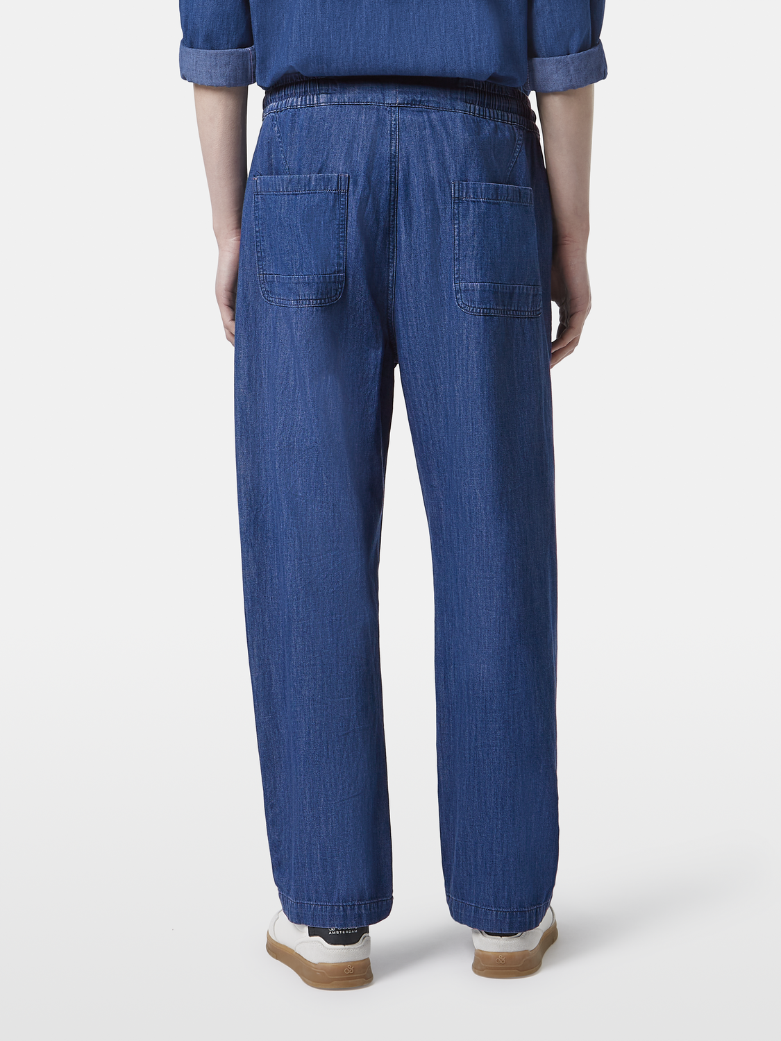 Lightweight denim pants from Scotch & Soda with back pockets and relaxed fit, shown hanging on a clothing rack.