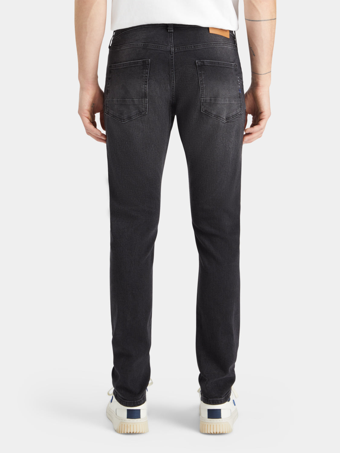 Dark wash Ralston slim-fit denim jeans by Scotch & Soda, showing the back view with classic stitching and leather patch.