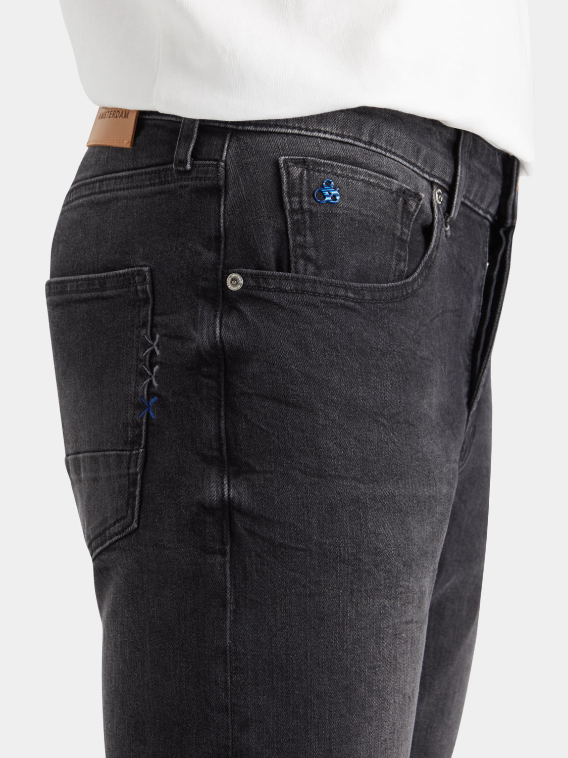 Pair of Scotch & Soda Ralston slim-fit denim jeans shown on a model, featuring classic blue wash and tapered leg style.