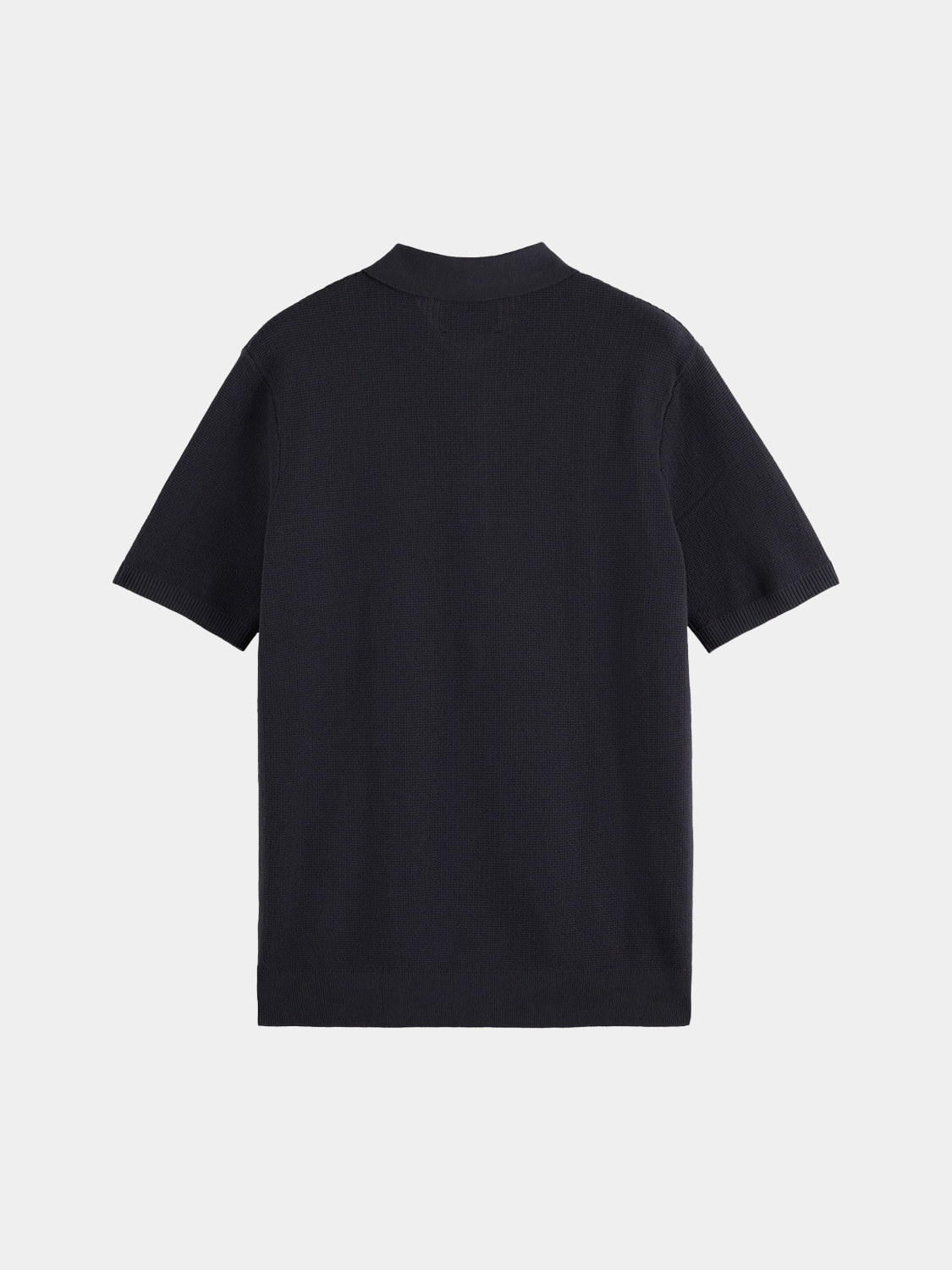 Black knitted polo shirt by Scotch & Soda, showing the textured fabric and classic collar detail.