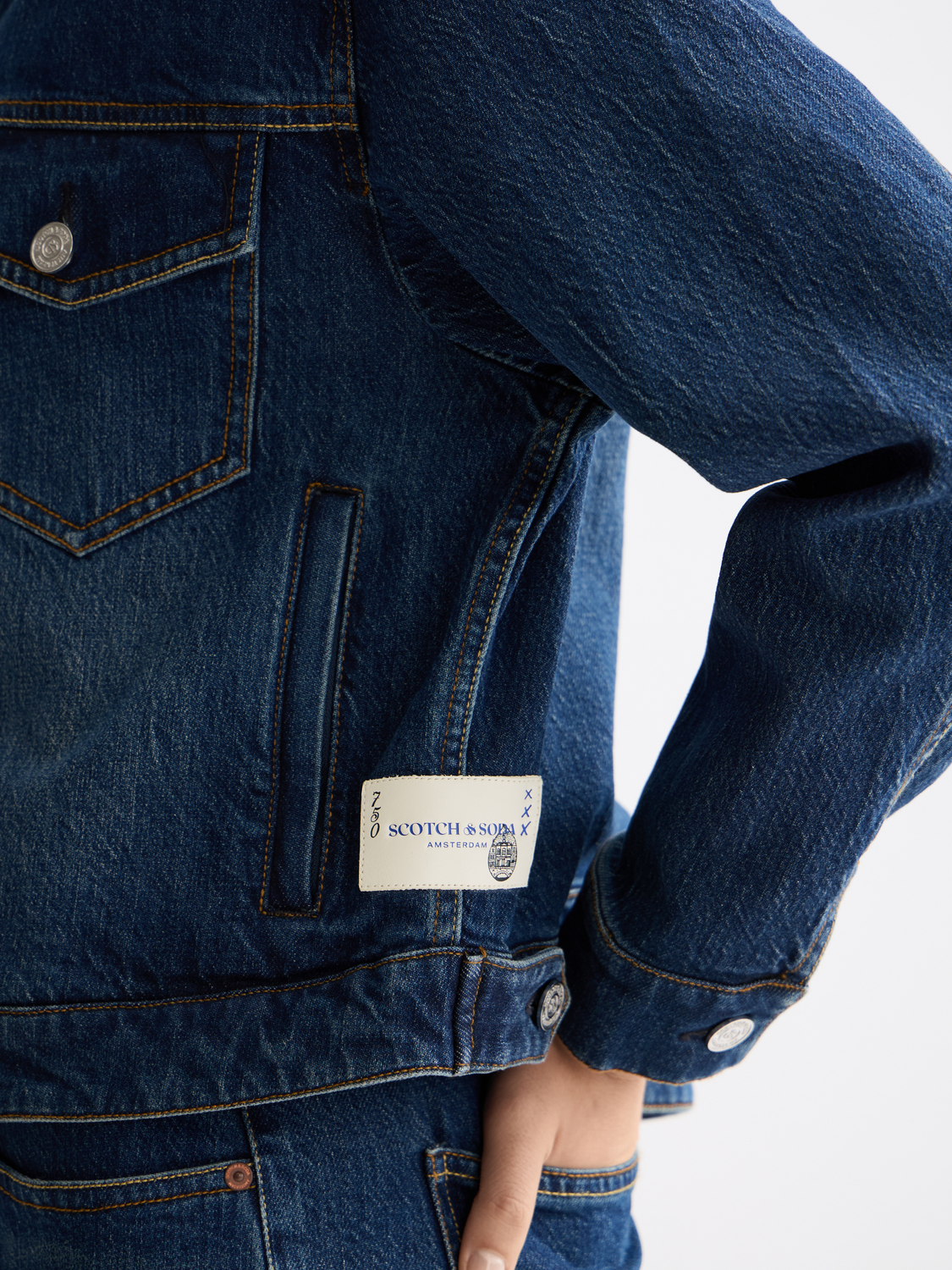 Light blue cropped denim jacket by Scotch & Soda with classic collar and button front, styled with rolled sleeves.