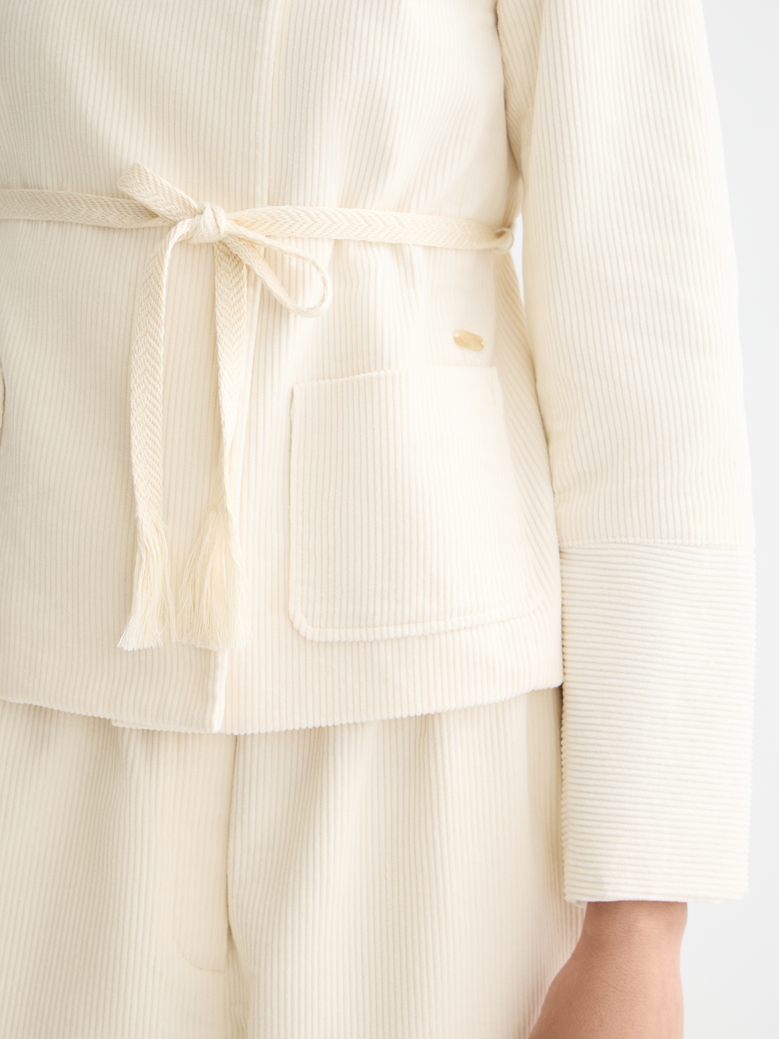 Scotch & Soda belted collarless blazer with tailored fit and structured design, shown in a neutral fabric with front button details.