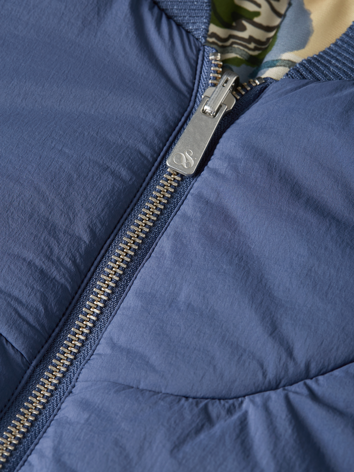 Reversible Scotch & Soda bomber jacket with contrasting fabric, front zipper, and ribbed cuffs, displayed on a hanger.