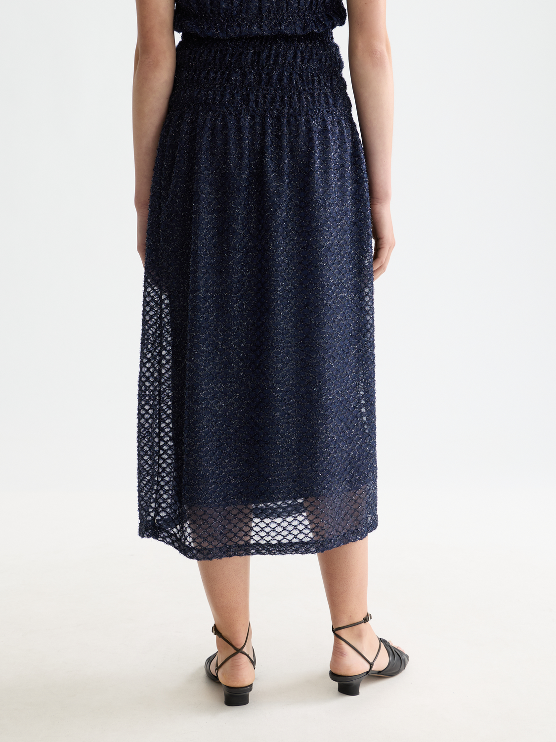 Black Lurex midi skirt by Scotch & Soda featuring a shimmering metallic finish and a flowing, elegant silhouette.