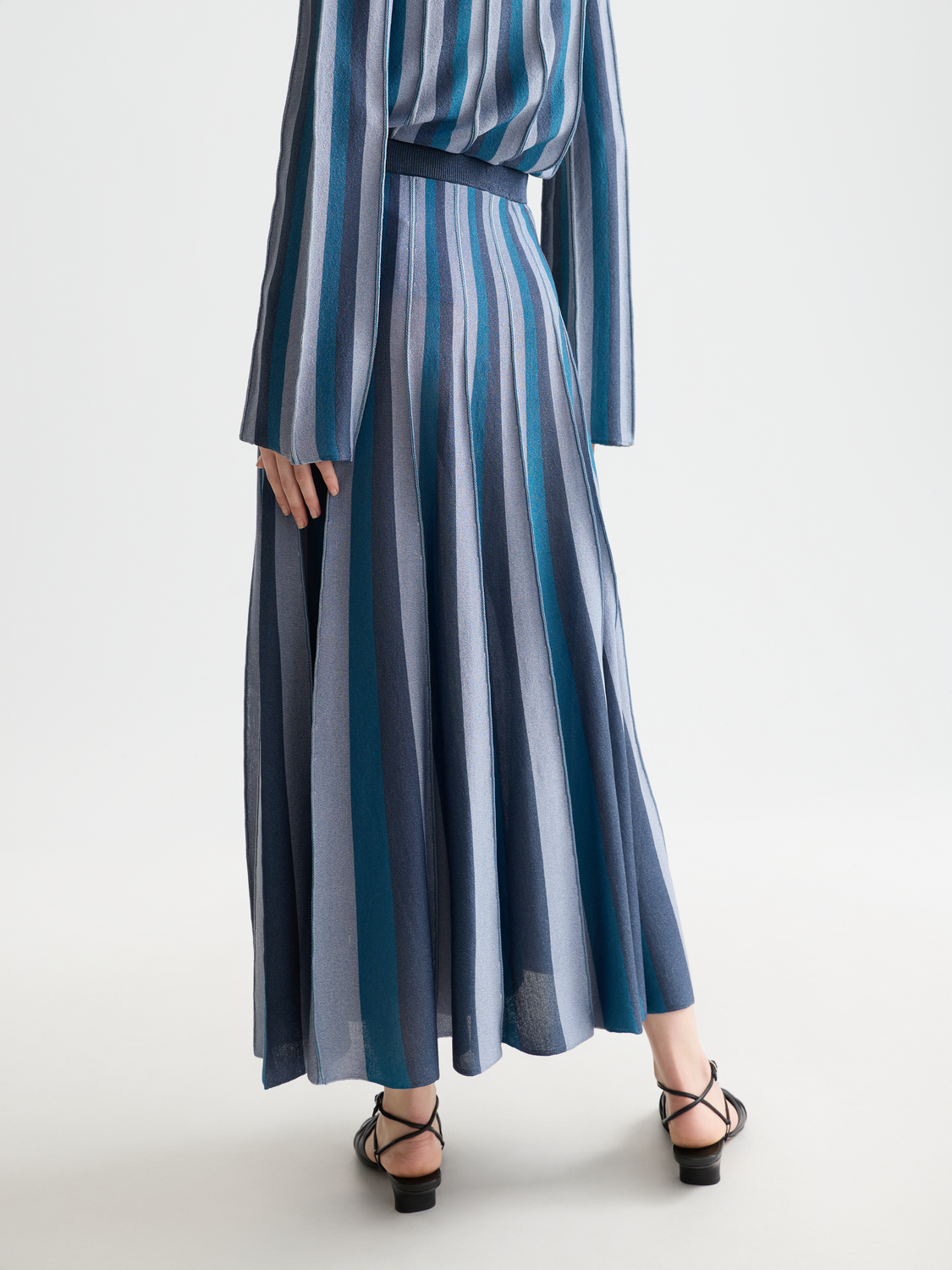 Black pleated knit midi skirt by Scotch & Soda, shown from the back with a flowy, textured design and midi length.