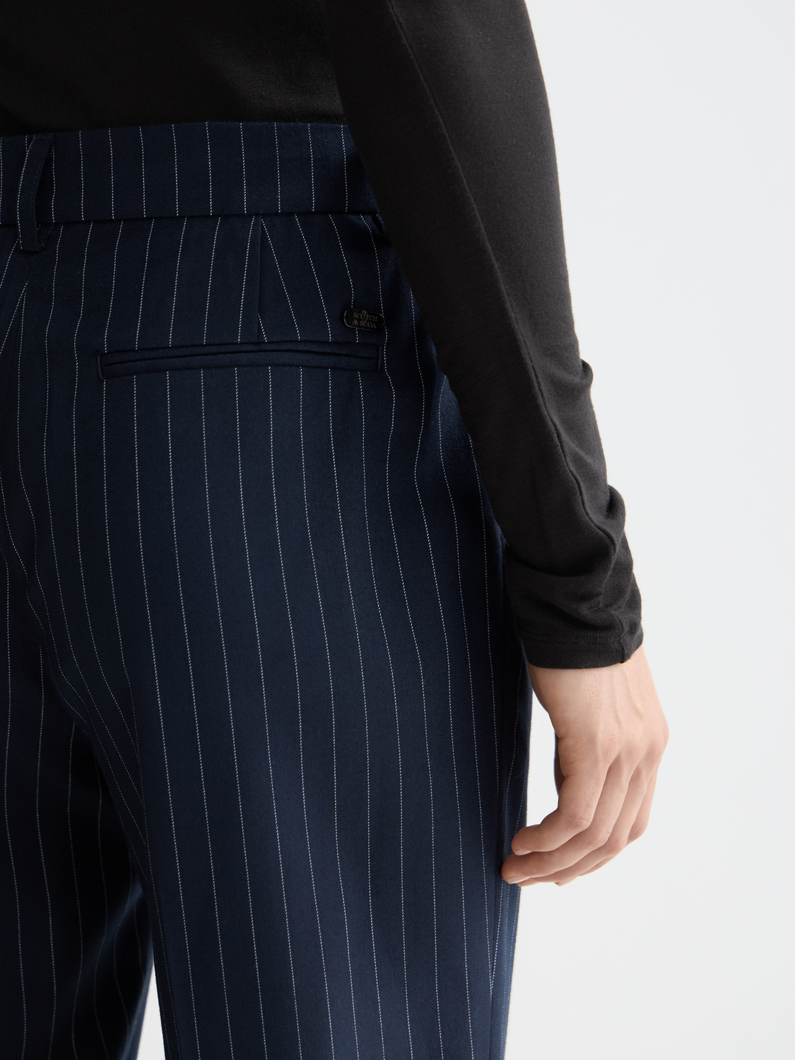 Slim-fit Lowry pants by Scotch & Soda, shown in dark denim with front pockets and belt loops, on a model.