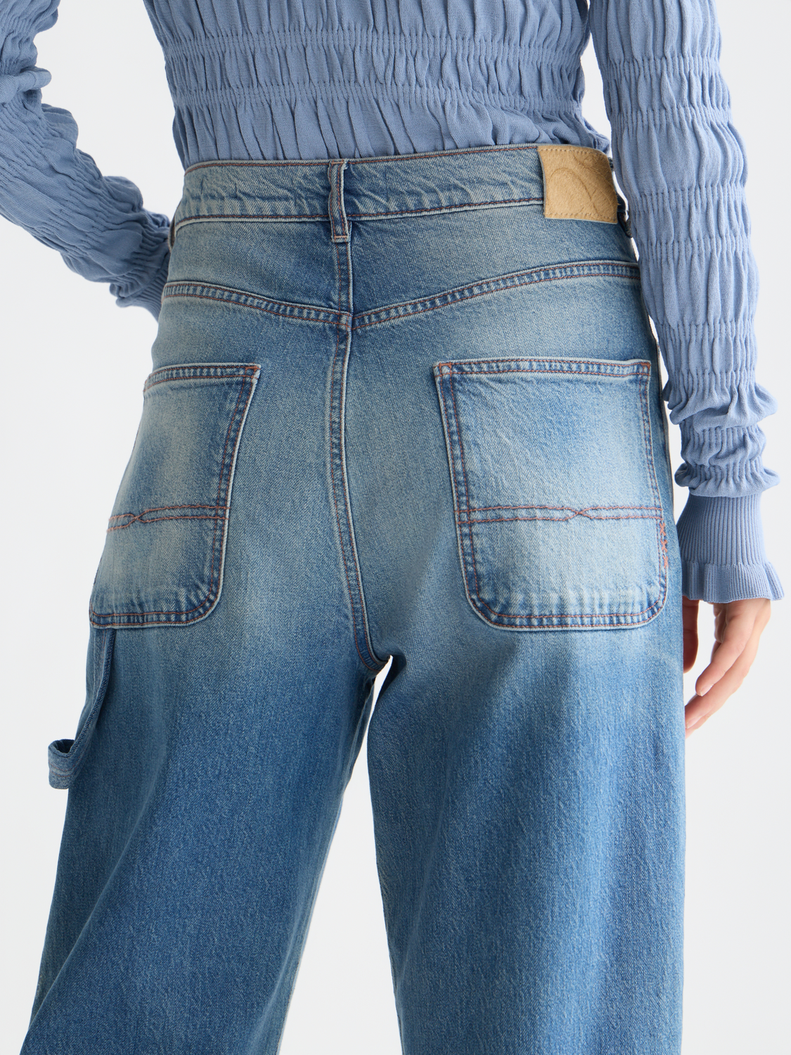 Scotch & Soda Raine wide-fit denim jeans hanging on a rack, showcasing their relaxed fit and classic blue denim fabric.