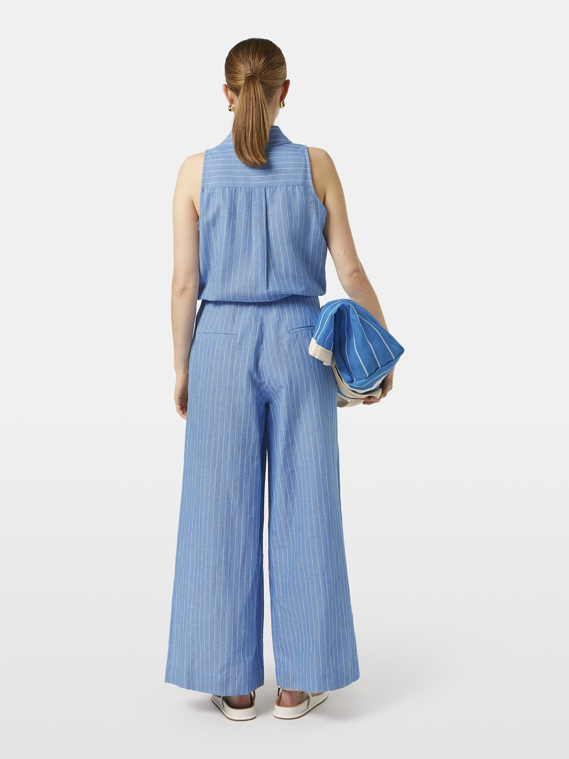 Striped linen jumpsuit by SCOTCH & SODA featuring a relaxed fit, with vertical stripes in blue and white, and a sleeveless design.