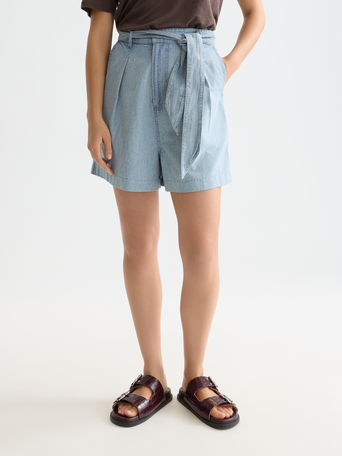 Blue denim shorts by Scotch & Soda with a rolled hem and classic five-pocket design, modeled on a person.