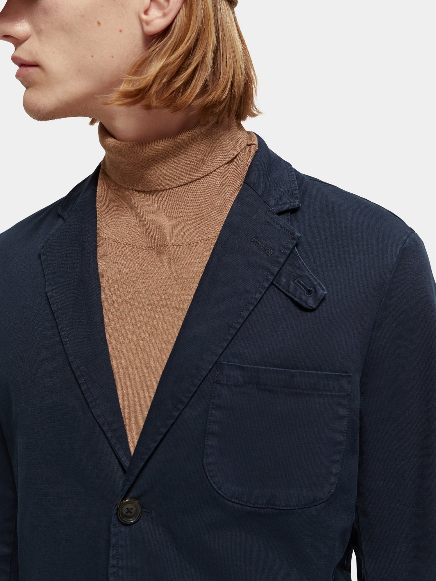 Structured cotton-blend blazer in garment-dyed fabric from SCOTCH & SODA, shown on a hanger with a tailored fit and detailed stitching.